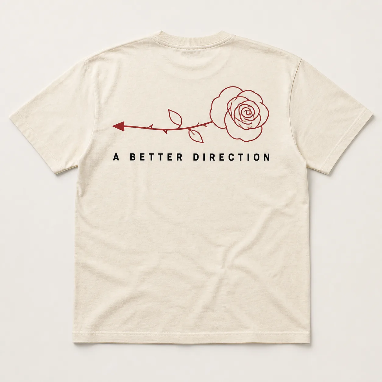 Back of a cream heavyweight tee with a large dark red line-drawn rose and the words A BETTER DIRECTION printed beneath it